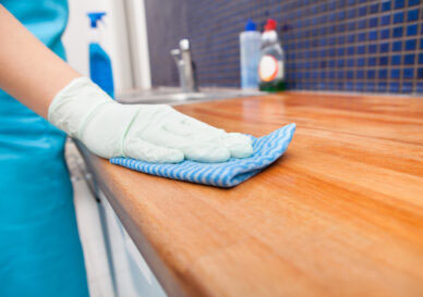 Closeup Of Young Woman Wearing Apron Cleaning Kitchen Worktop